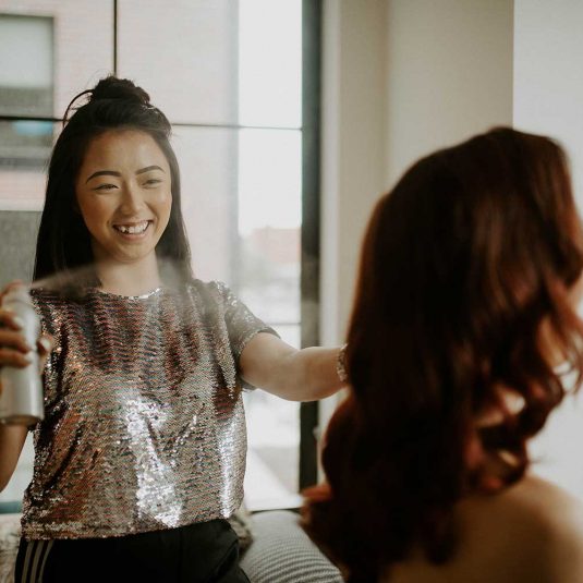 hairstylist spraying product onto hair of woman