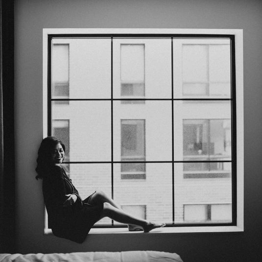 smiling woman sitting on window sill