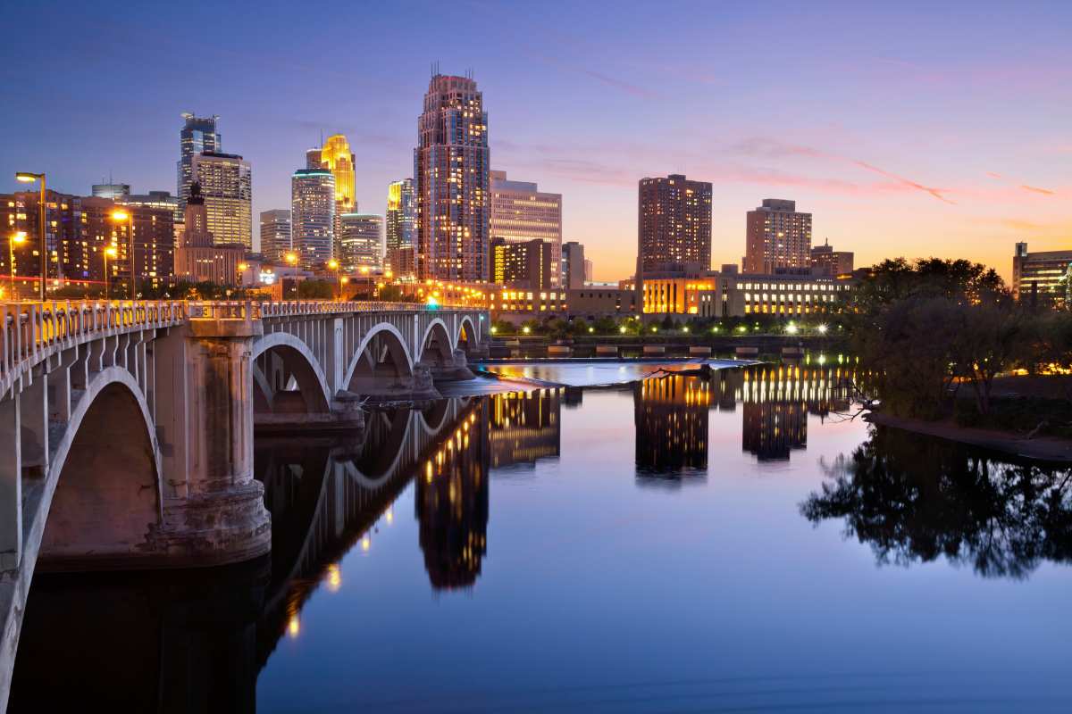 arch bridge spanning river with city skyline in background