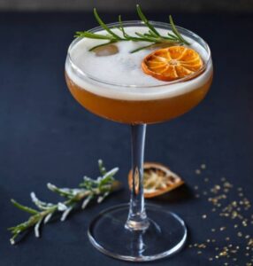 seasonal holiday cocktail garnished with rosemary and orange