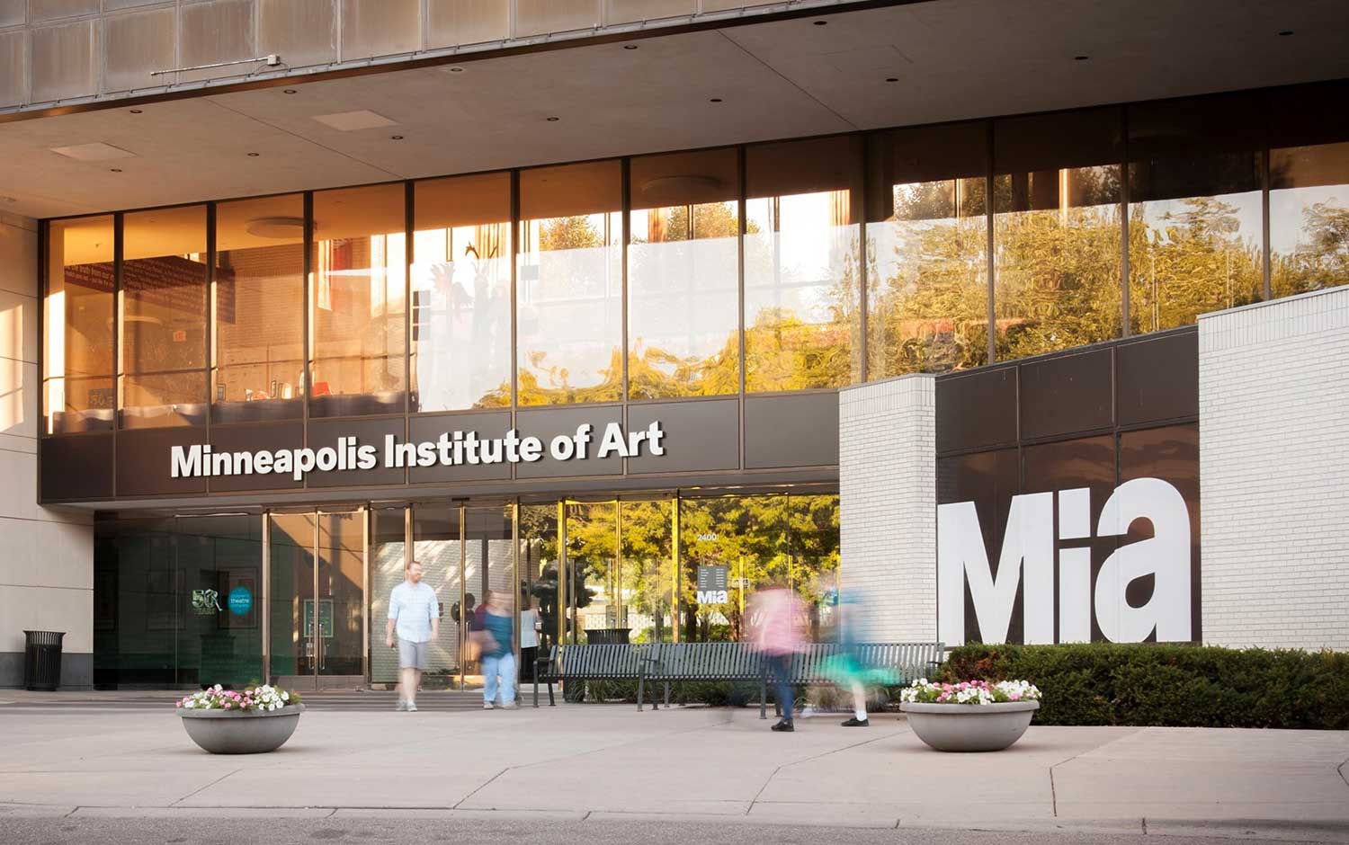 Entrance to the Minneapolis Institute of Art, a renowned art museum, featuring large glass windows, clear signage, and people walking outside in Minneapolis.
